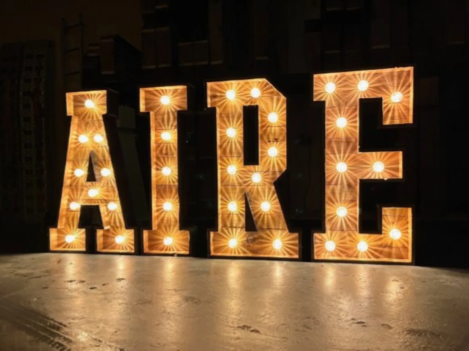 Rustic light up letters spelling AIRE with warm amber bulbs