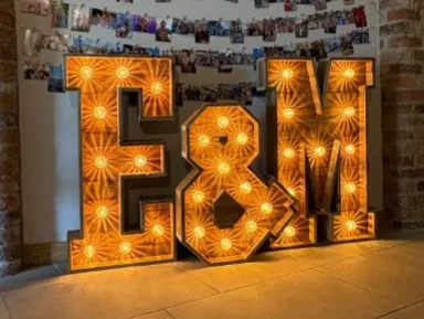 Rustic light up E & M initials glowing amber at a wedding