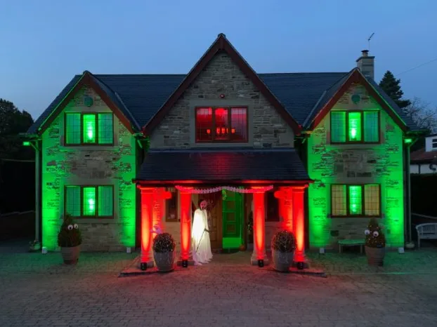 Green and red uplighting on a country house exterior