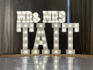 White MR & MRS TAIT light up letters at a wedding reception