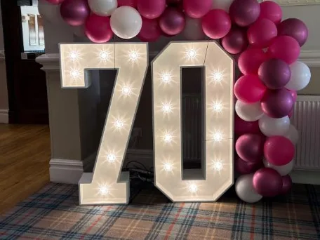 White light up number 70 with a balloon garland